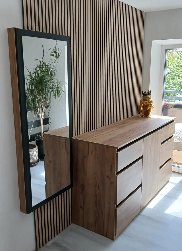 Komoda s dřevěnou deskou před lamelovou stěnou se zrcadlem